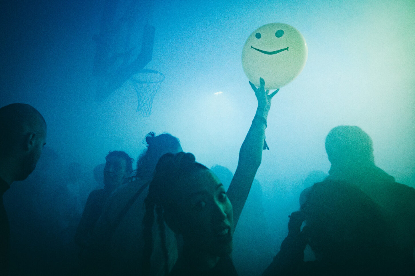 Girl engulfed by fog holds up a yellow balloon with smiley face at Sustain-Release.