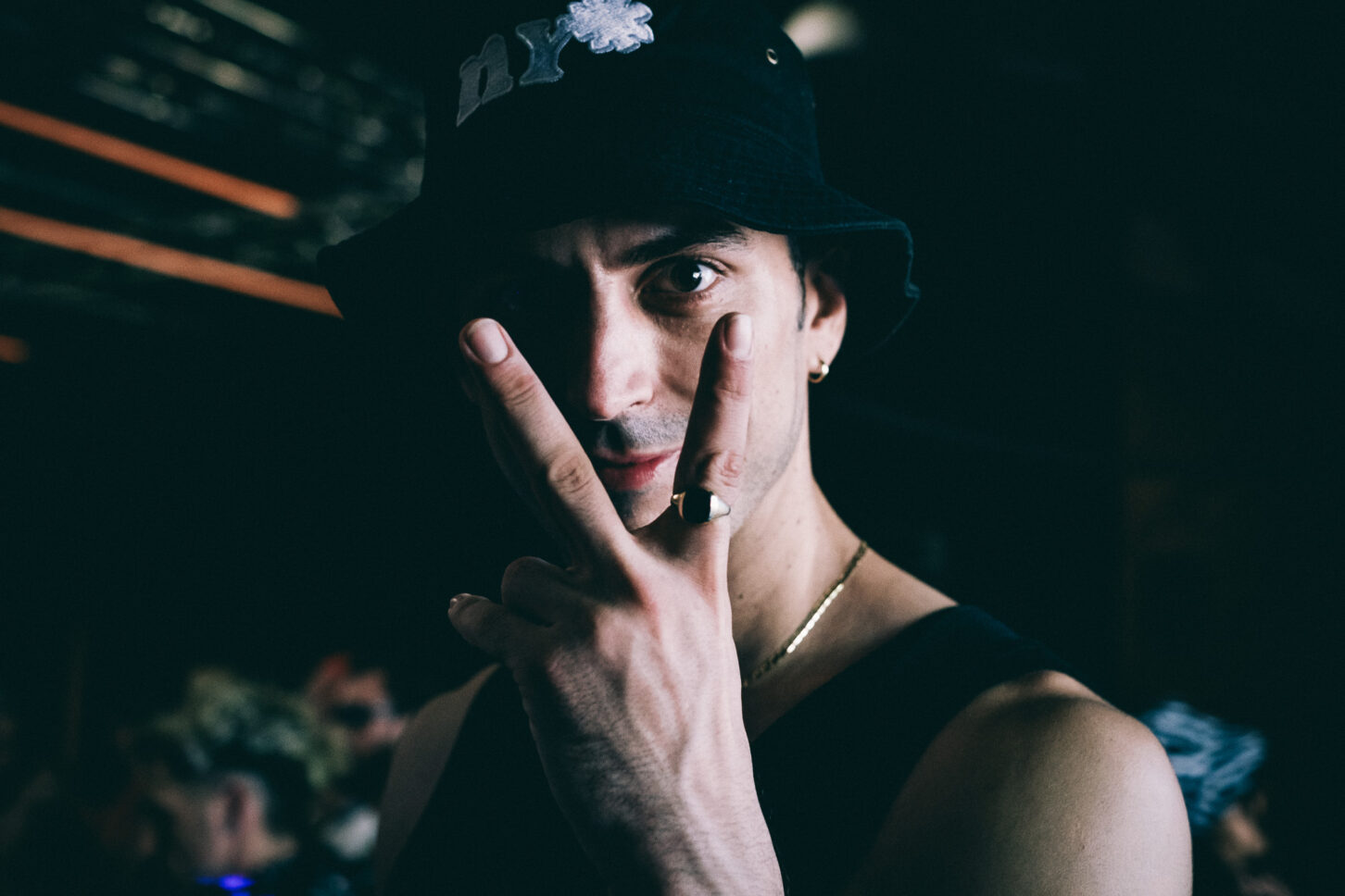 Man wearing a bucket hat shows a peace sign to the camera.