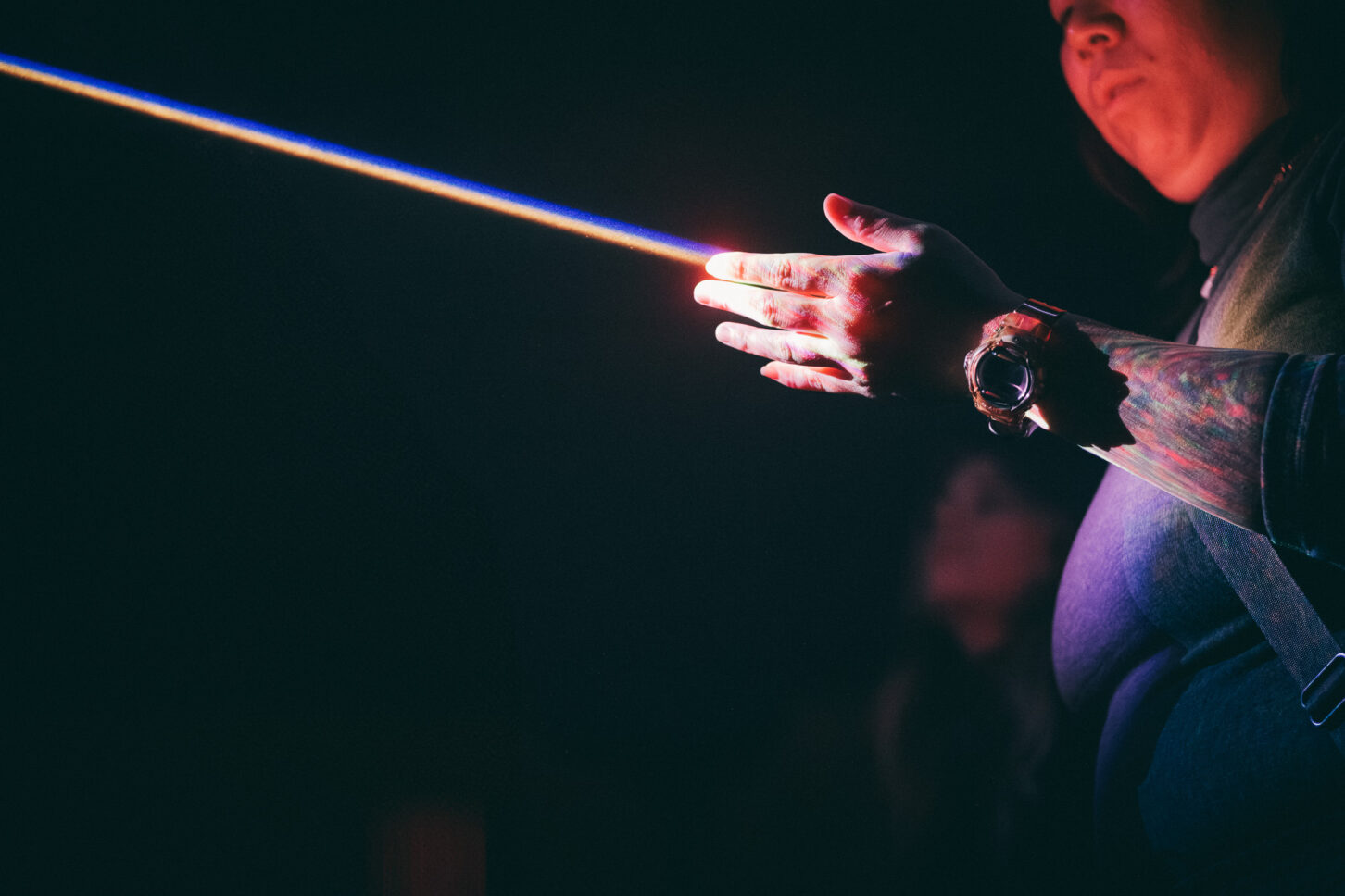 A woman touches a laser light with her hand while she examines it closely during Sustain-Release.