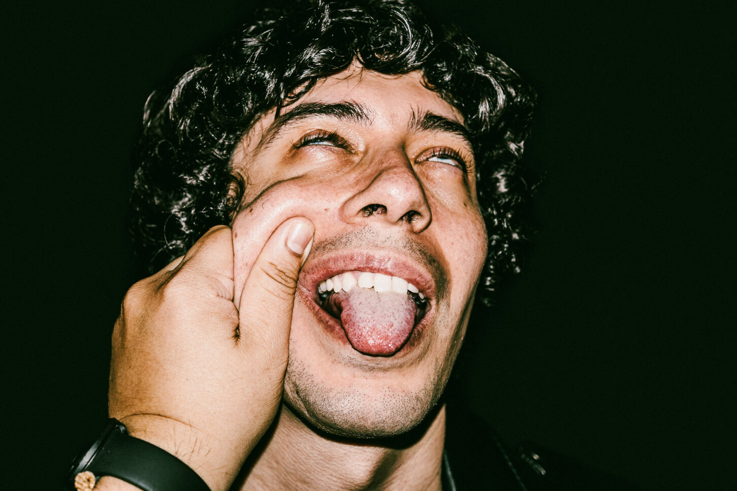 A subject sticking their tongue out playfully in a rebellious, gritty portrait for the 'Cheeky Bastards' series.