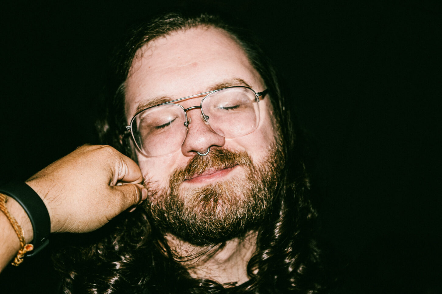 A person with a stoic, deadpan expression that contrasts humorously with the hand pinching their cheek, captured in the gritty 'Cheeky Bastards' style.