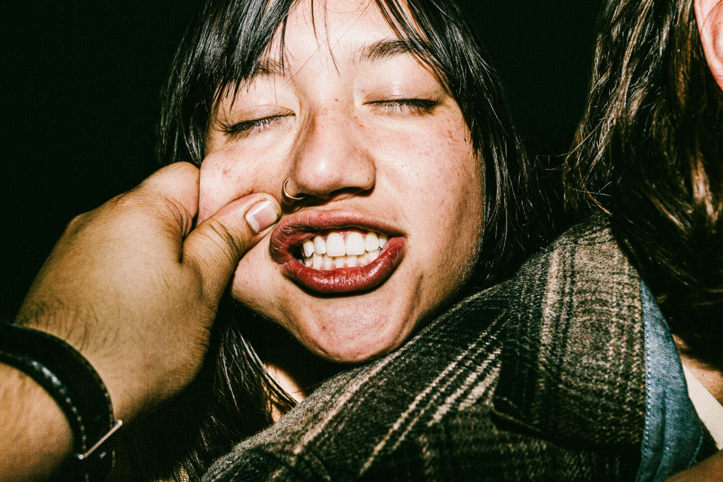 A subject making a goofy, exaggerated "duck face" reaction to a cheek pinch in this gritty, high-contrast 'Cheeky Bastards' photo.