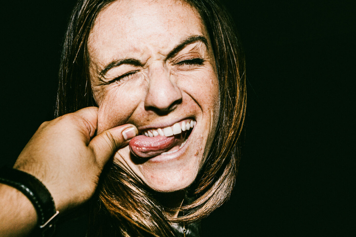 A subject sticking their tongue out playfully in a rebellious, gritty portrait for the 'Cheeky Bastards' series.