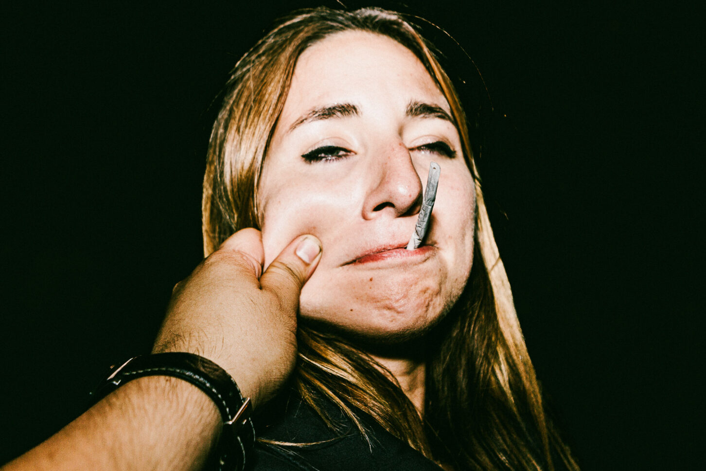 A subject attempting to keep a straight face but failing, with a smirk breaking through in this 'Cheeky Bastards' close-up.