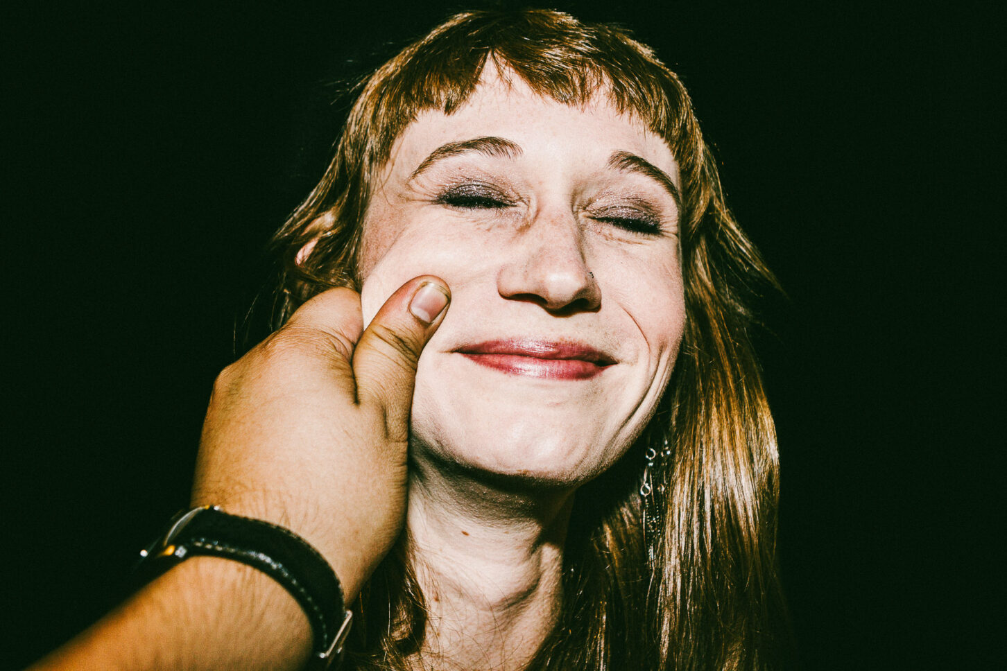 A subject attempting to keep a straight face but failing, with a smirk breaking through in this 'Cheeky Bastards' close-up.