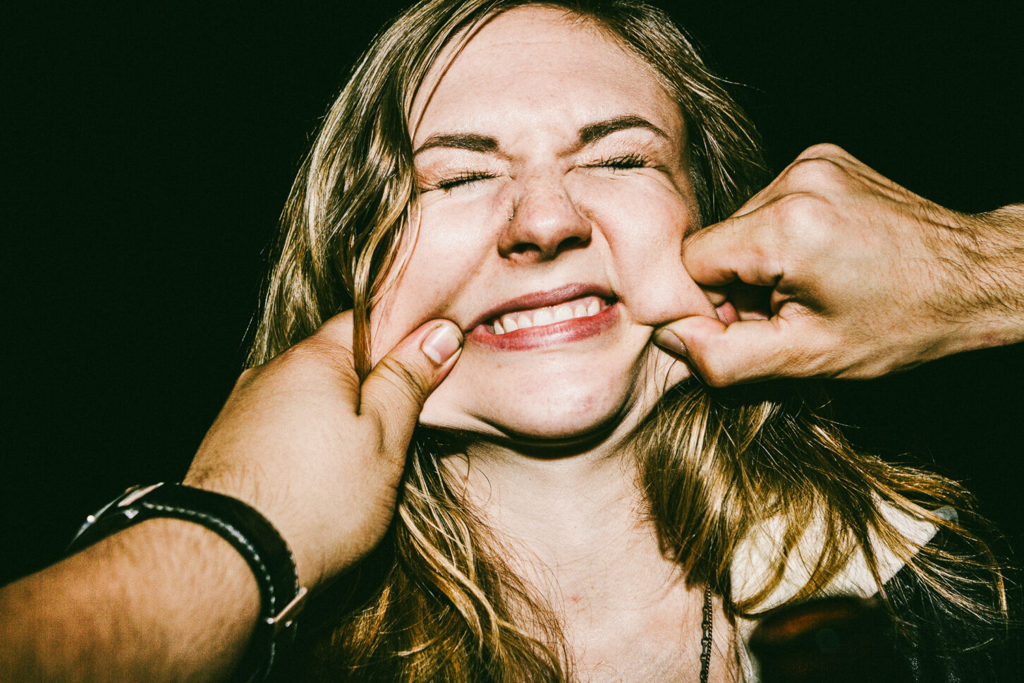A person with an exaggerated, playful look of shock in a close-up flash portrait, highlighting the raw human narrative of the 'Cheeky Bastards' series.