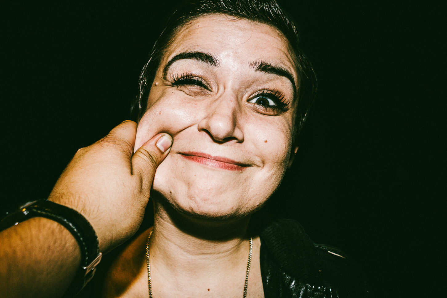 A dynamic, blurry motion shot of a subject pulling away from the pinch laughing, capturing the chaotic energy of the 'Cheeky Bastards' shoot.