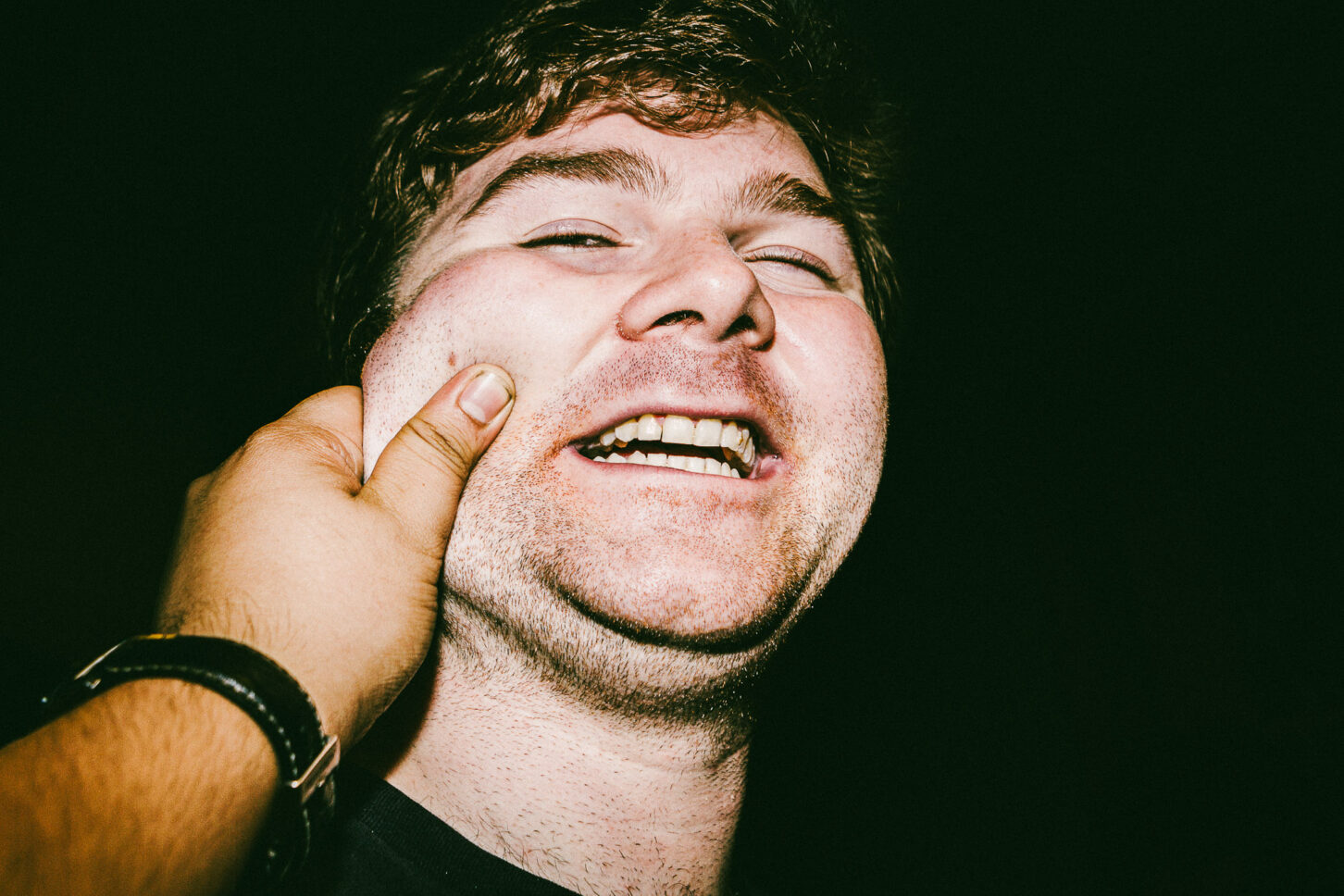 A man roaring with laughter, head thrown back, in a high-energy flash portrait from the 'Cheeky Bastards' collection.