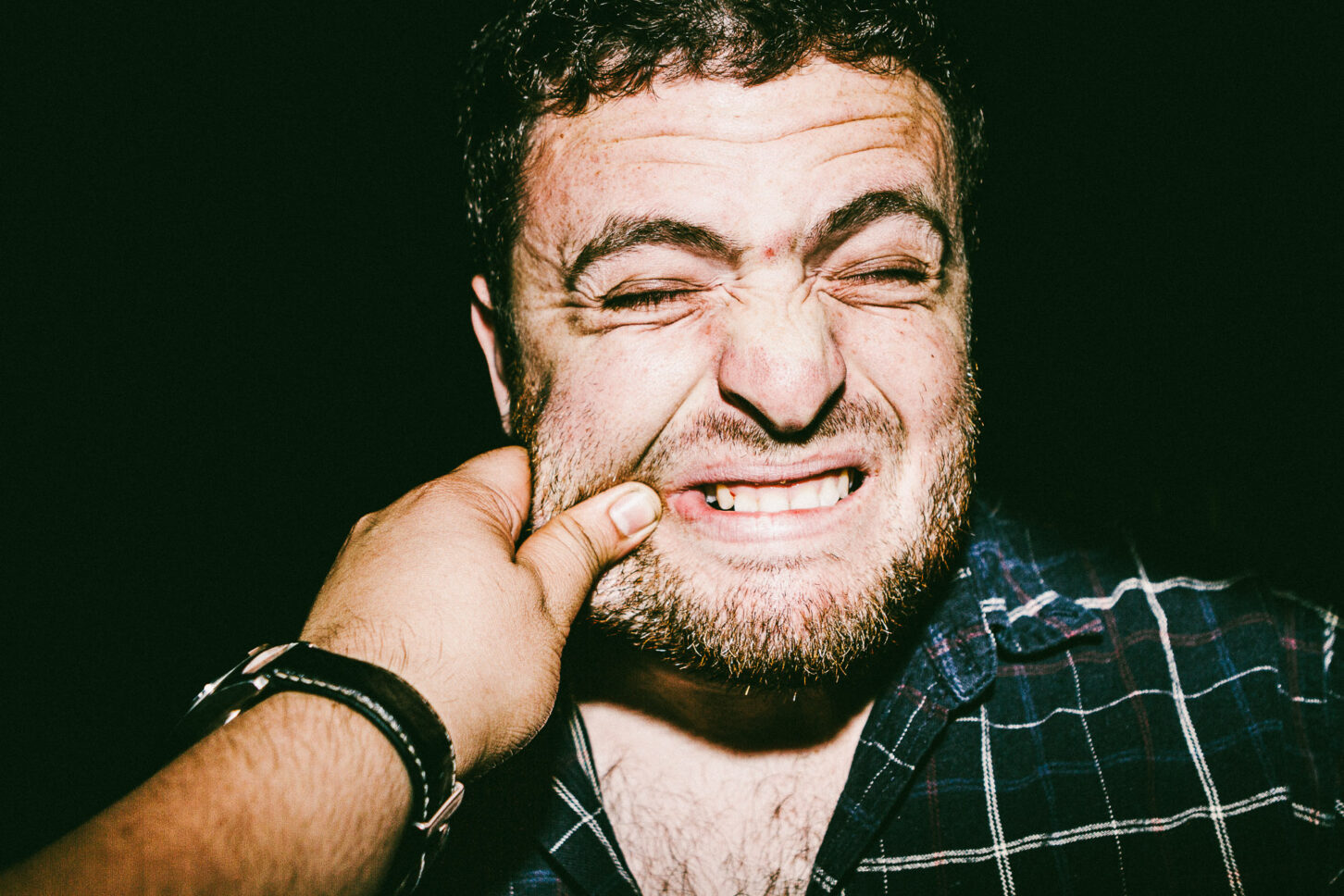 A person biting their lower lip in a "cringe" expression that feels both funny and raw, part of the 'Cheeky Bastards' photo series.