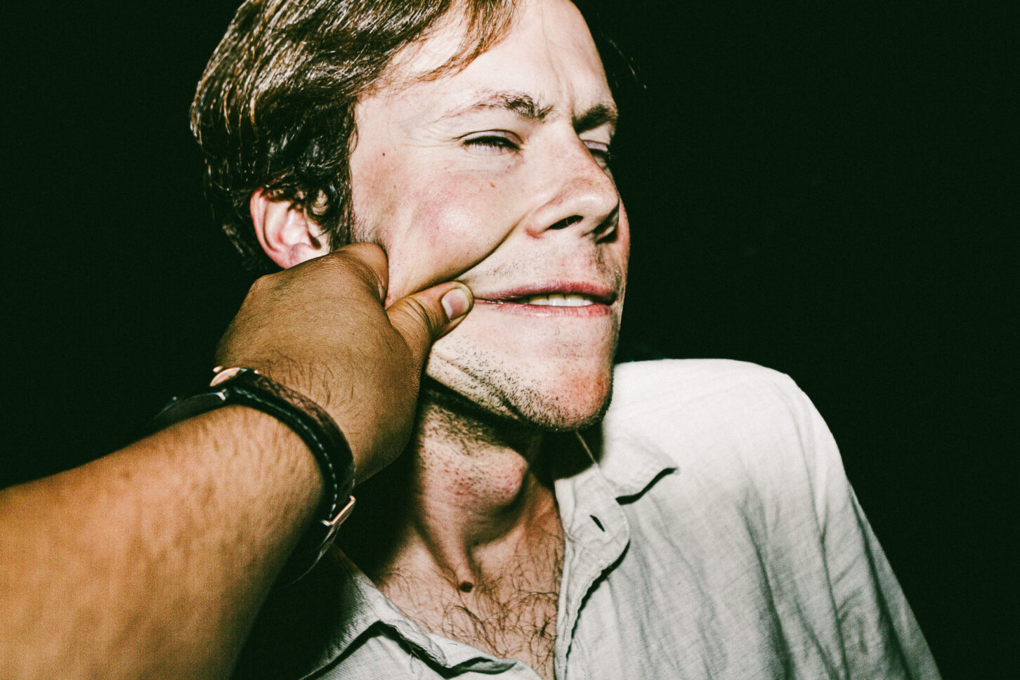 A subject pressing their face into the pinch, exaggerating the distortion for a grotesque and funny 'Cheeky Bastards' portrait.