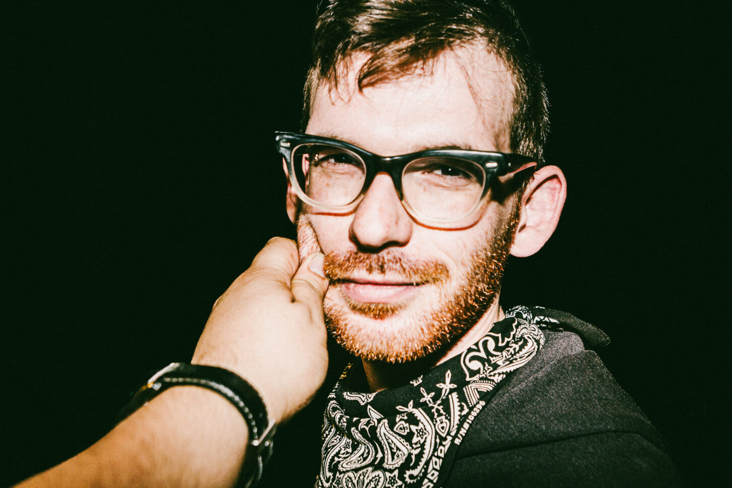 A person looking straight at the camera with a "dare you" intensity, even while getting their cheek pinched in this 'Cheeky Bastards' shot.