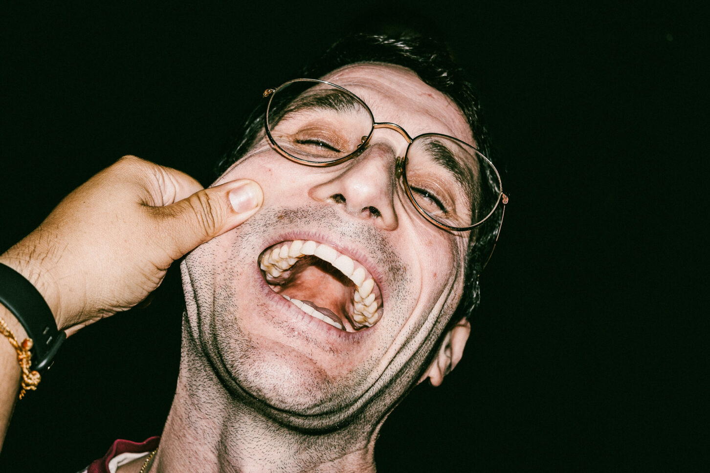 A man roaring with laughter, head thrown back, in a high-energy flash portrait from the 'Cheeky Bastards' collection.